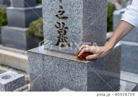 お墓参りに来てたわしでお墓の掃除をしている男性 80938759