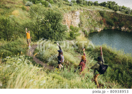 Beautiful landscape. Group of friends, young men and women walking, strolling together outskirts of city, in summer forest, meadow. Active lifestyle, friendship, care, ecology concept Beautiful landscape. Group of friends, young men and women walking, strolling together outskirts of city, in summer forest, meadow. Active lifestyle, friendship, care, ecology concept 80938953