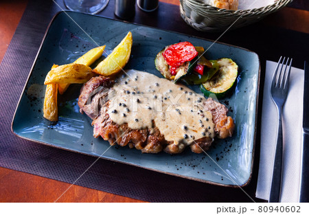 Veal steak with piquant creamy sauce, potatoes and vegetables 80940602