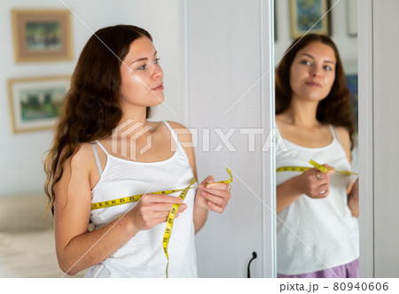 Happy young woman measuring breasts with measuring tape 80940606