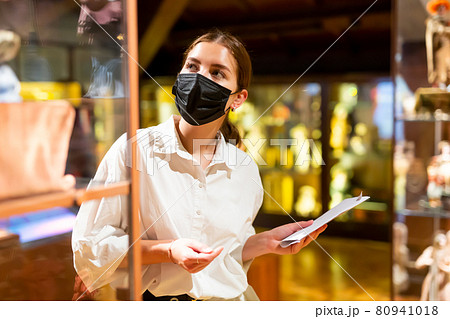 Woman exploring artworks in glass case in museum 80941018