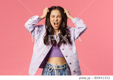 Portrait of furious young pissed-off girl losing her mind, distressed pull hair from head and screaming, grimacing look angry and hateful, standing stressed over pink background 80941352