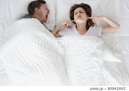 Young man lying in bed and shouting at woman with closed ears top view Young man lying in bed and shouting at woman with closed ears top view 80942662
