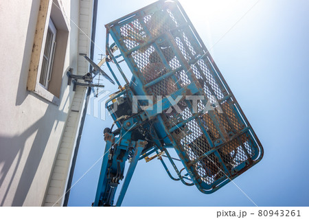 Worker on a aerial access platform, cherry picker, cleaning house Worker on a aerial access platform, cherry picker, cleaning house 80943261