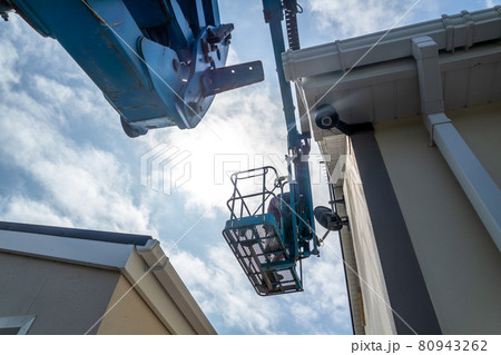 Worker on a aerial access platform, cherry picker, cleaning house Worker on a aerial access platform, cherry picker, cleaning house 80943262