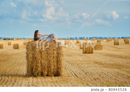 Calm young woman laying on the top of the ricks on the field Calm young woman laying on the top of the ricks on the field 80943526