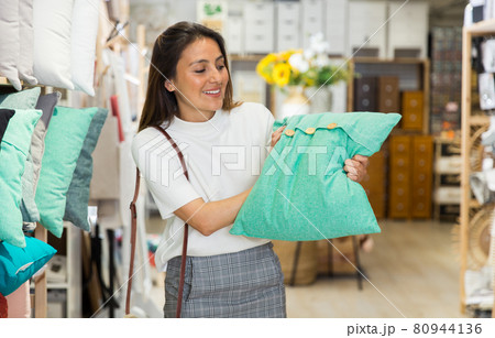 Woman choosing pillow at household goods store Woman choosing pillow at household goods store 80944136
