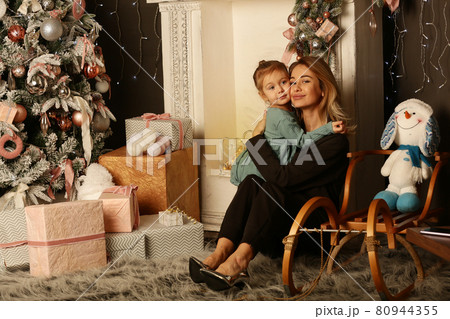 cute little blond baby girl and mom on Christmas tree and fire place background 80944355