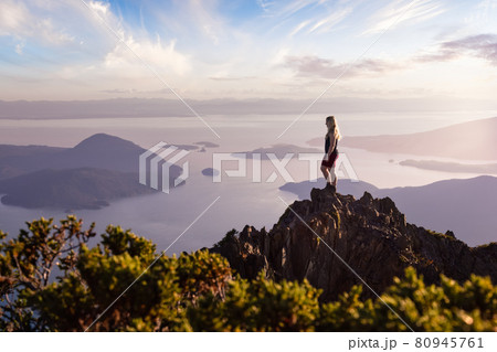 Adventurous Caucasian Woman Hiking on top of a Rocky Mountain Cliff. 80945761