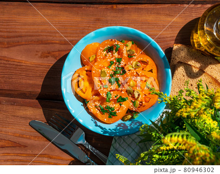 Yellow tomatoes salad with rye bread slices in blue ceramic bowl top view. Ripe fresh colorful vegetables mixed greens 80946302