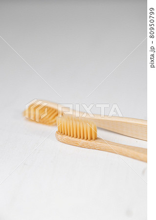 daily human hygiene, cotton swabs and cotton pads, a woman's hand holding bamboo toothbrushes on a light background in a glass or against the background of a wooden tray 80950799