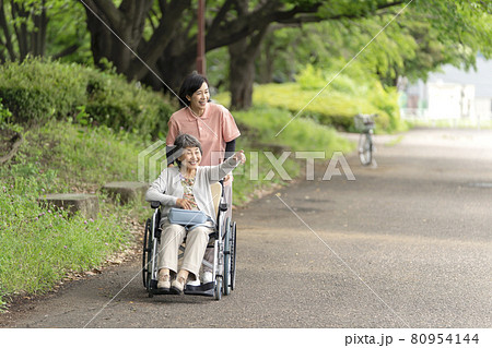 公園で散歩する車椅子のシニア女性と介護士 80954144
