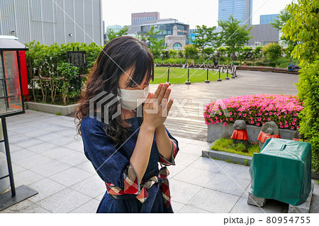 つつじが咲く銀座出世地蔵尊でお祈りするマスク姿の若い女性 80954755