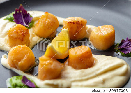 Scallops in creamy sauce on black plate 80957008