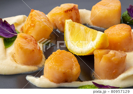 Scallops in creamy sauce on black plate 80957129