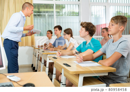 Focused teenage students studying in classroom with teacher Focused teenage students studying in classroom with teacher 80958458