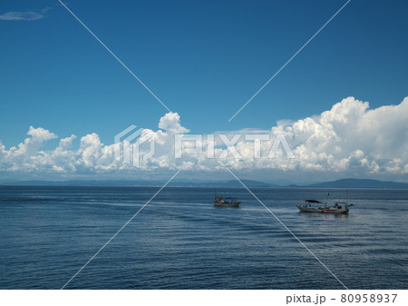 紺碧の空に浮かぶ白い雲静かな海面に停泊する漁船 80958937