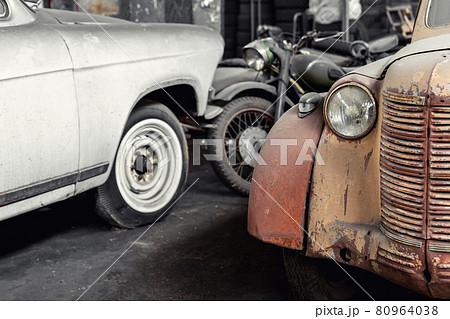 Many rusty abandoned forgotten antique oldtimer old car and motorcycles at junkyard factory storage warehouse indoors. Classic vintage retro vehicles detail garage workshop restore renovation station 80964038