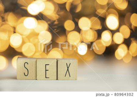 Three wooden cubes with letters SEX on them with colorful gold shiny bokeh background. 80964302