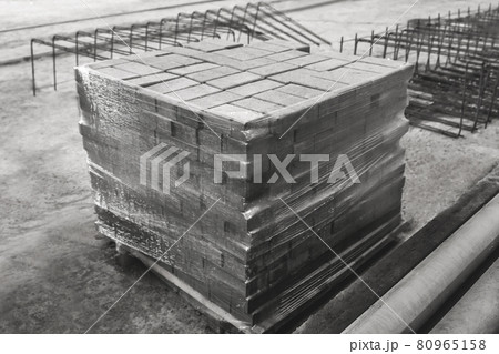 Concrete blocks packed in cellophane film at a construction site. Concrete bricks in an industrial area. Storage paving stone on warehouse 80965158