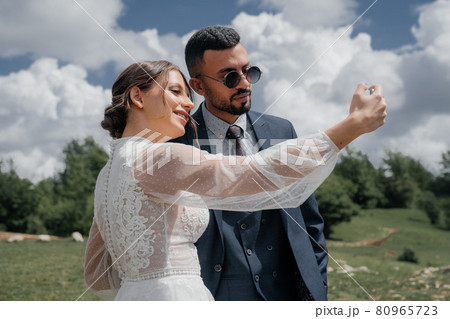 the bride and groom take a selfie together. wedding broadcast online.  80965723