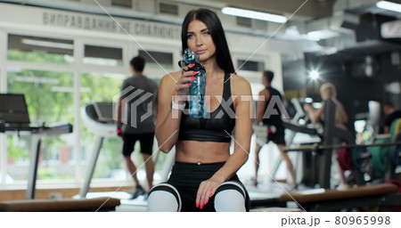 Beautiful sporty woman drinks water in fitness gym after workout exercise or training building muscles - healthy concept. Body Healthy Lifestyle in Fitness Gym. 80965998