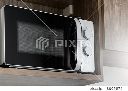 Close-Up White microwave on a wooden shelf in kitchen, Can Reheat Food Qickly in the Microwave. 80966744
