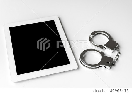 タブレット端末と手錠。サイバー犯罪のイメージ タブレット端末と手錠。サイバー犯罪のイメージ 80968452