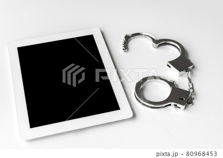タブレット端末と手錠。サイバー犯罪のイメージ タブレット端末と手錠。サイバー犯罪のイメージ 80968453