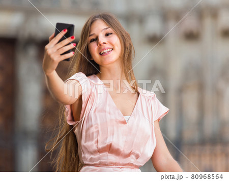 female standing in the street and taking selfie 80968564