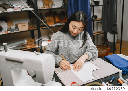 Professional young female tailor working in workshop 80970320