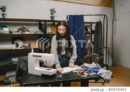 Professional young female tailor working in workshop 80970402