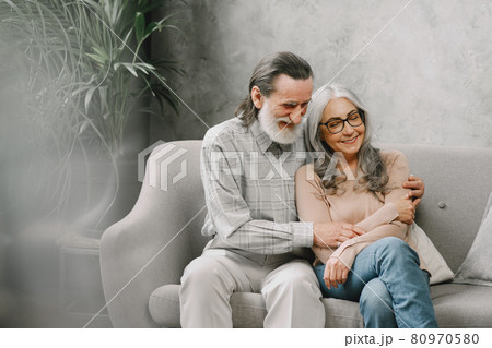 Senior couple in casual clothes sitting on couch in living room 80970580