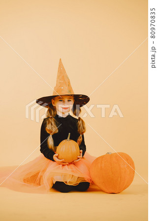 Beautiful girl witch on a orange background Beautiful girl witch on a orange background 80970835