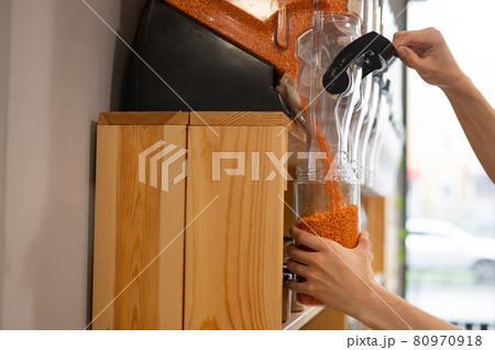 A man fills a jar with red lentils. Selling bulk goods by weight in an eco store. Trade concept without plastic packaging 80970918