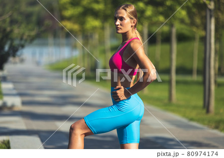 Young slim sportive caucasian woman working out, doing fitness, yoga in the park or on city street. 80974174