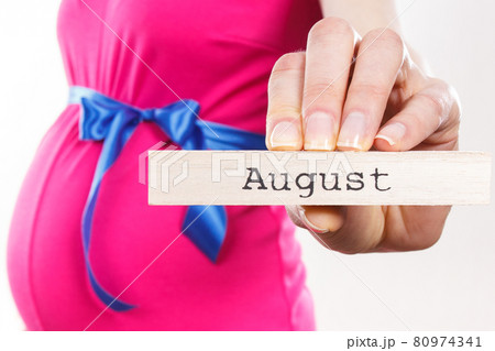 Woman in pregnant wearing pink dress with blue ribbon and showing word august Woman in pregnant wearing pink dress with blue ribbon and showing word august 80974341