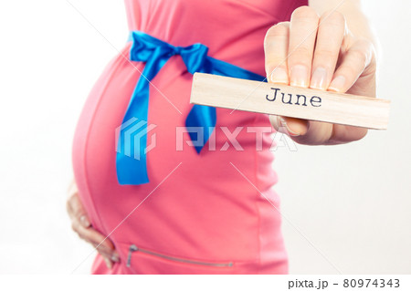 Woman in pregnant wearing pink dress with blue ribbon and showing word june 80974343