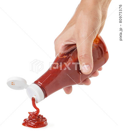 Ketchup squeezes out of a bottle hand on a white background. Isolated 80975376