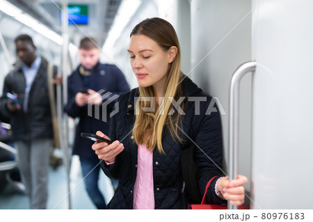 Girl using mobile phone in metro car Girl using mobile phone in metro car 80976183