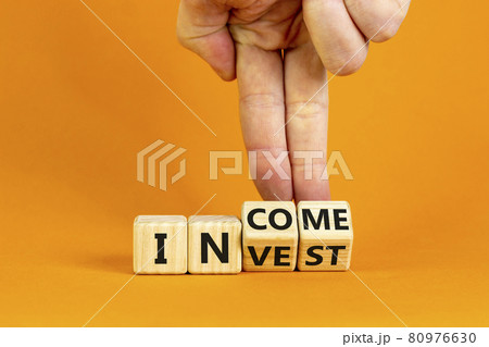 Invest or income symbol. Businessman turns wooden cubes and changes the word 'invest' to 'income'. Beautiful orange background, copy space. Business and invest or income concept. 80976630