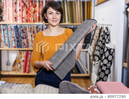 Saleswoman arranging cloth rolls 80977290