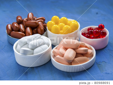 A group of vitamins on a blue background. 5 types of dietary supplements of different colors A group of vitamins on a blue background. 5 types of dietary supplements of different colors 80988691