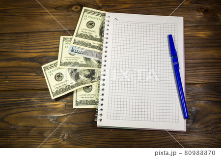Notebook with ballpoint pen and dollar banknotes on the wooden desk 80988870