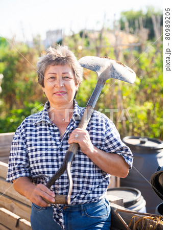 Mature woman having horticultural instruments in garden on day 80989206