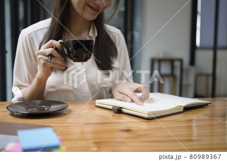 Smiling young woman drinking hot coffee and reading book at home. Smiling young woman drinking hot coffee and reading book at home. 80989367