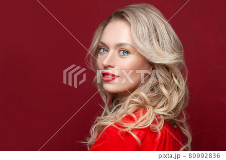 Smiling female model on red background. Pretty woman with makeup and curly hair portrait 80992836