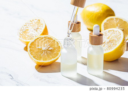 Lemon essential oil in glass bottles, white marble background. Skin and body care concept. 80994235