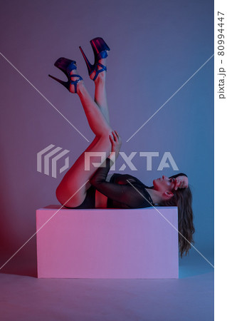 young woman pole dancer posing on a cube in the style of synch wave 80994447