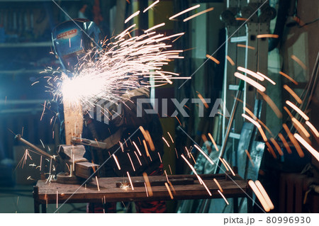 Man in mask cuts metal with plasma cutter. Helmet and spakrs Man in mask cuts metal with plasma cutter. Helmet and spakrs 80996930